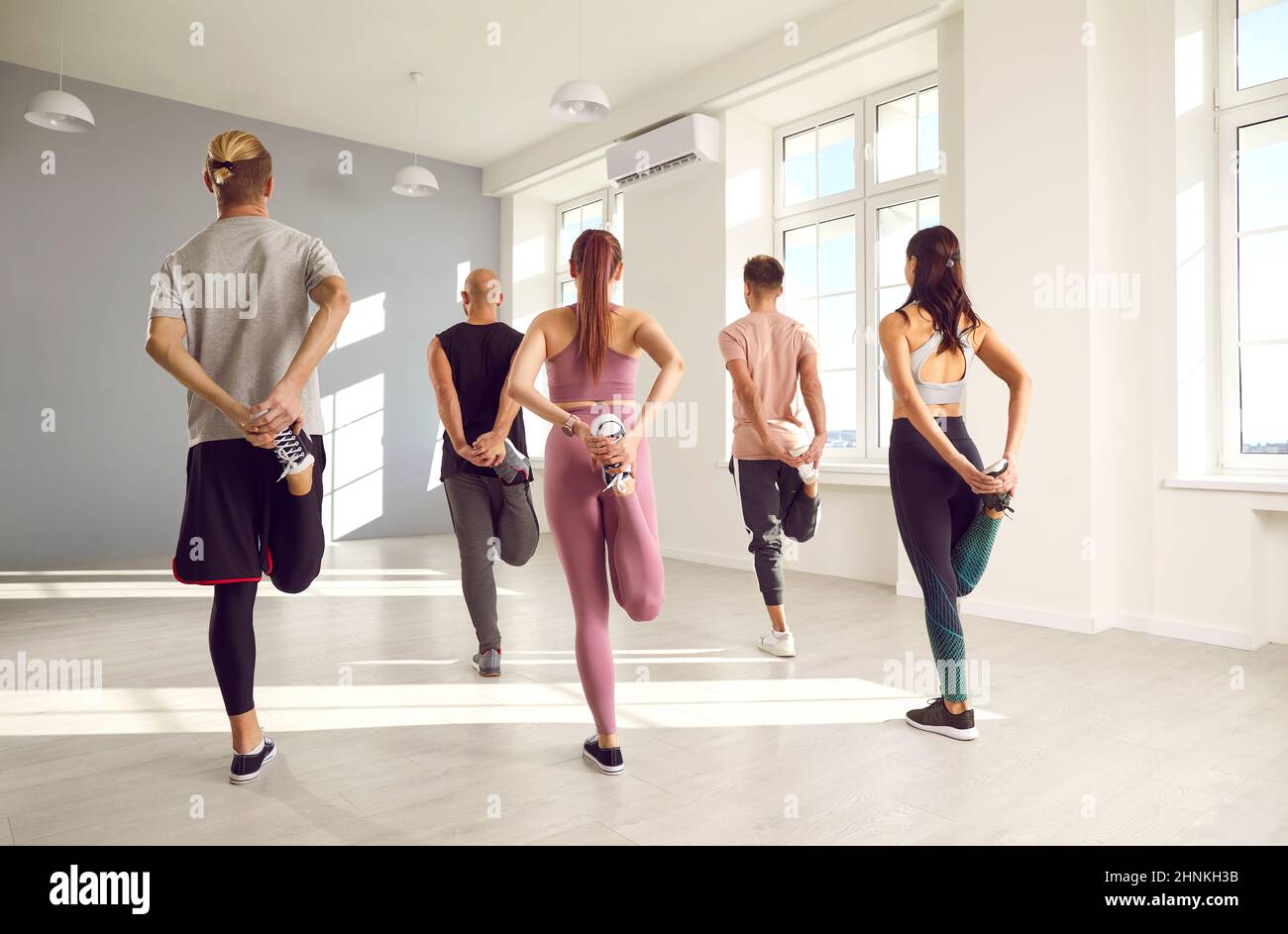 Eine Gruppe junger Menschen, die während eines Fitnesstrainings im Fitnessstudio Stretching-Übungen machen Stockfoto