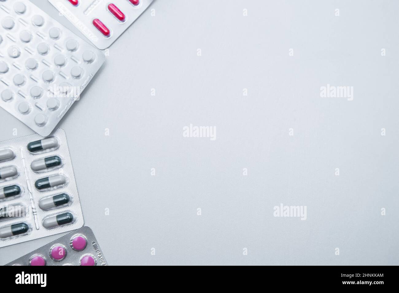 Tabletten und Kapseln in der Packung liegen auf der Seite auf weißem Hintergrund mit einem Platz für Text in der Mitte. Stockfoto
