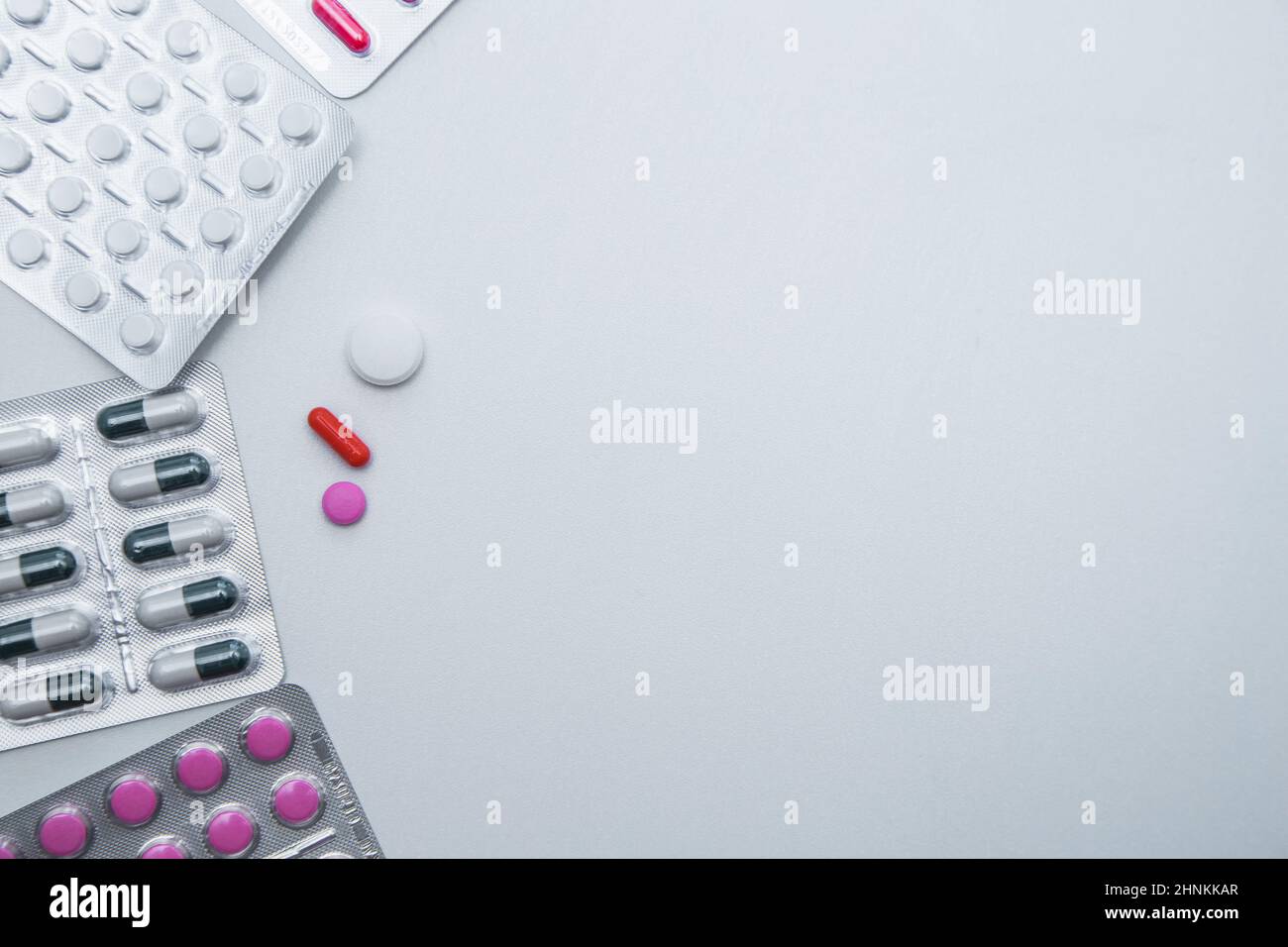Tabletten und Kapseln in der Packung liegen auf der Seite mit einer Handvoll Tabletten auf weißem Hintergrund mit einem Platz für Text in der Mitte Stockfoto