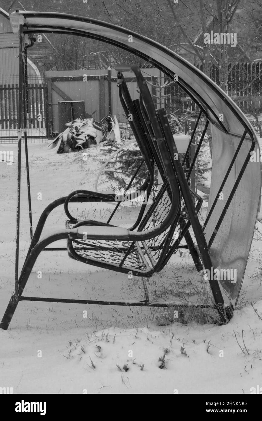 Schaukel in einem verschneiten Garten. Hinterhof eines Landhauses Stockfoto