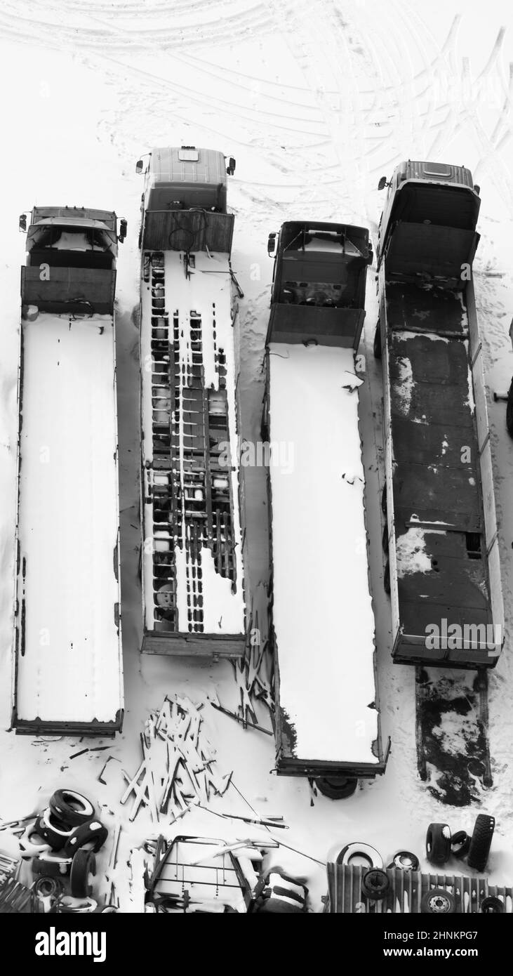 LKW unter dem Schnee. LKW mit Schnee bedeckt nach Schneefall. Lange Lastwagen stehen in einer Reihe Luftaufnahme. Transportkonzept. Schneebedeckte Fahrzeuge. Kopierraum Stockfoto