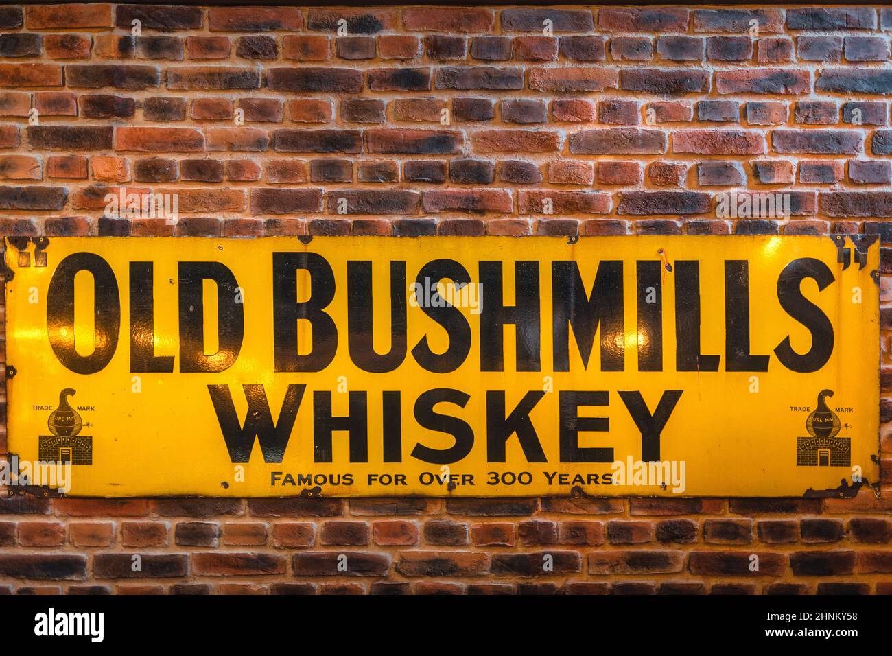 Old Bushmills Whiskey ist seit über 300 Jahren bekannt und steht auf einer rustikalen Ziegelmauer Stockfoto