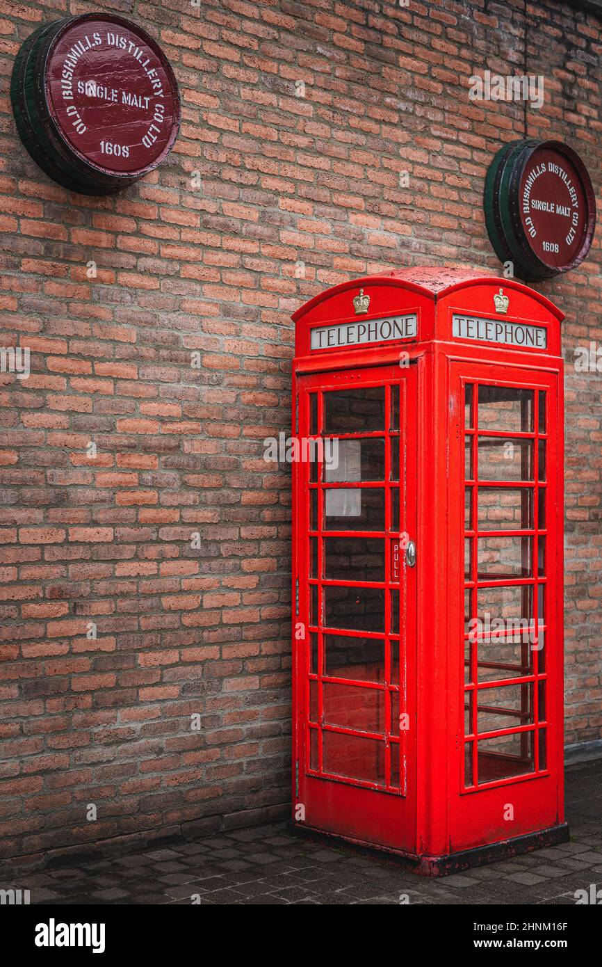 Traditionelle britische Telefonzelle mit Bushmills-Whiskey-Fässern oben Stockfoto