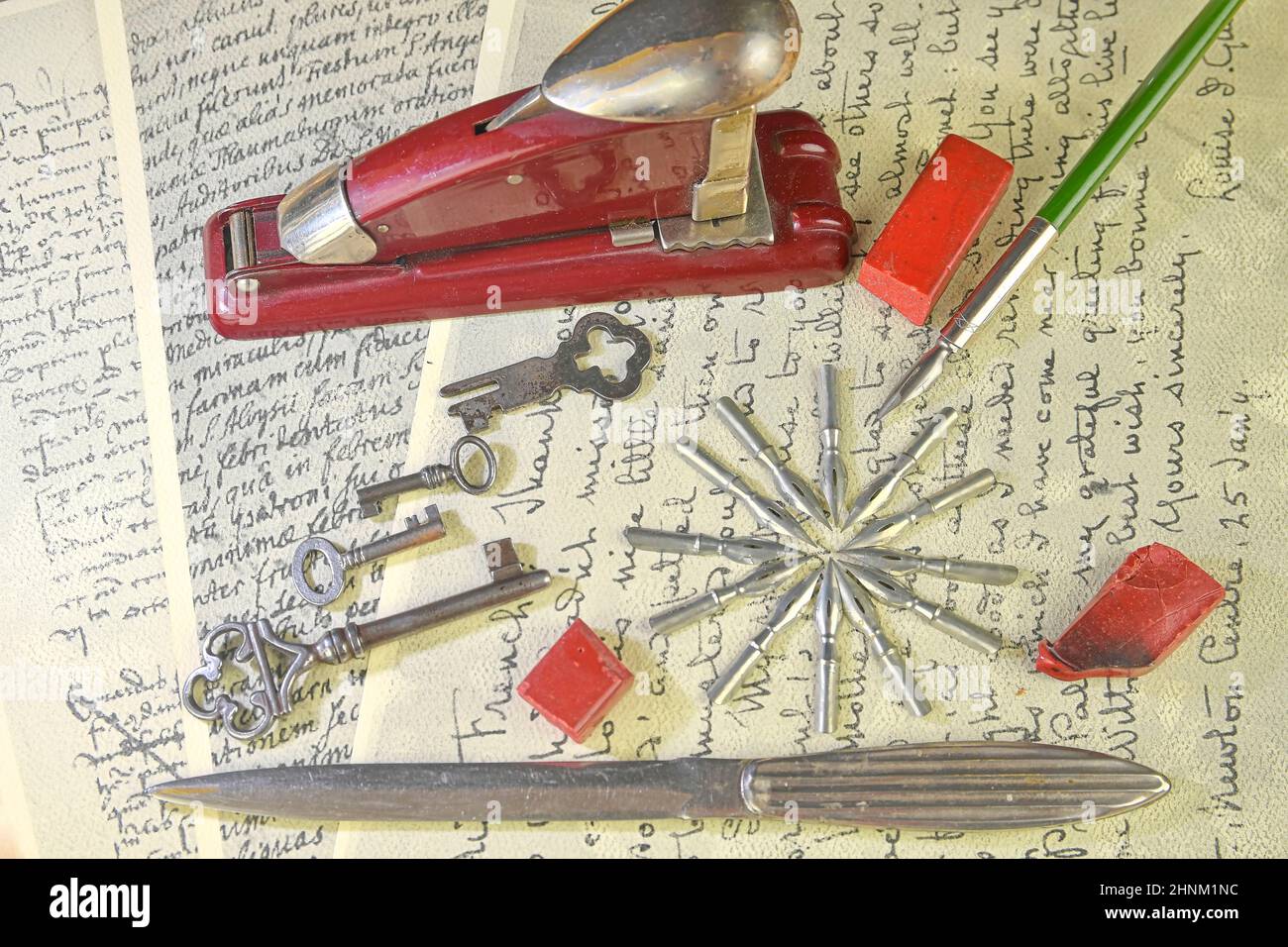 Nahaufnahme von Accessoires auf Vintage-Handschrift. Vintage-Schlüssel, Hefter, Siegelwachs, Papiermesser, Metallspitzen und alter Stift. Vintage-Schreibwaren. Flach liegend Stockfoto