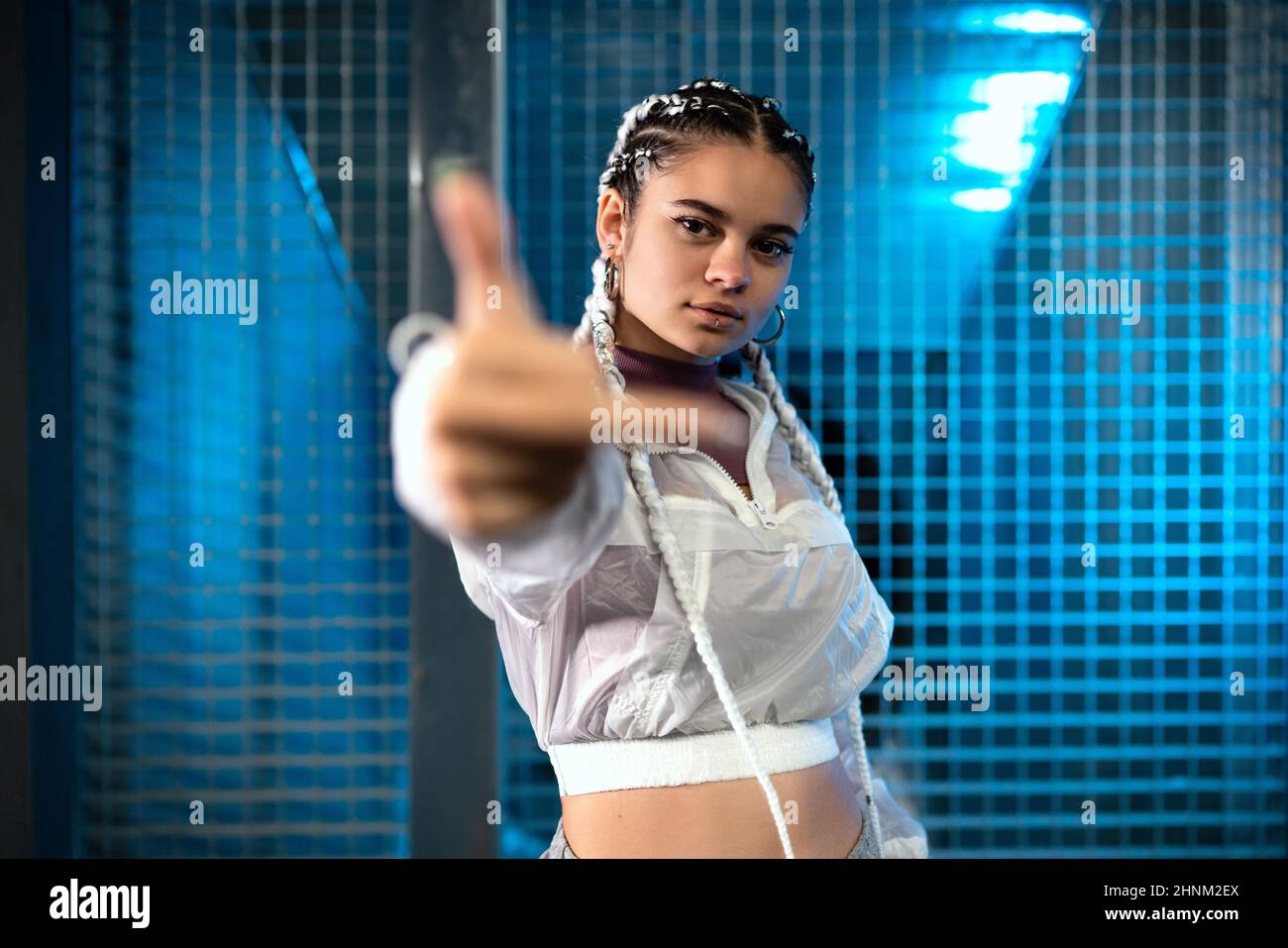 Junge Frau zeigt Mittelfinger seitlich zur Kamera mit blauem Licht im  Hintergrund Stockfotografie - Alamy