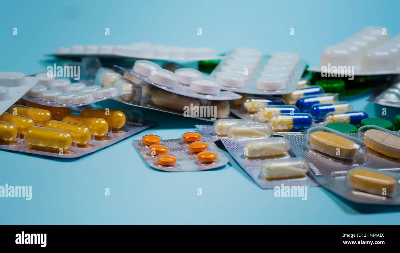 Pillen, Tabletten und Kapseln in verschiedenen Formen und Farben auf blauem Hintergrund. Stockfoto