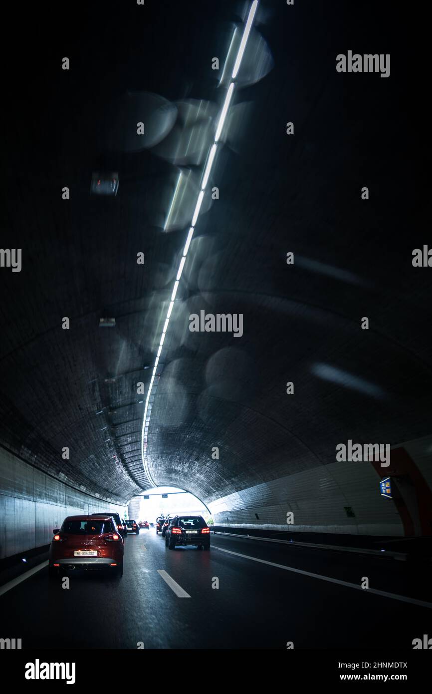 Autos auf einer Autobahn, die durch einen langen modernen Tunnel fahren (bewegungsunscharfes Bild, farblich getöntes Bild) Stockfoto