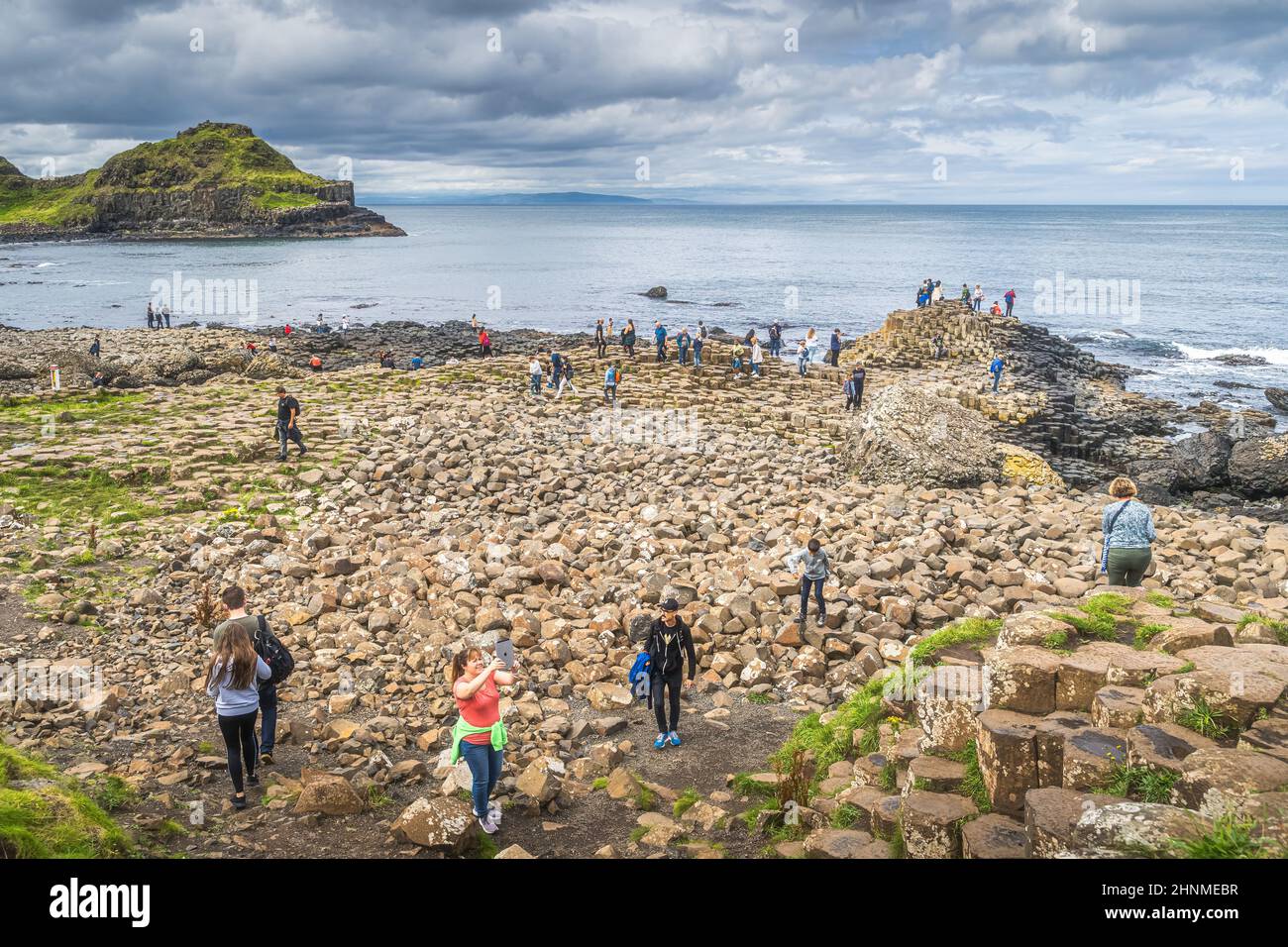 Touristen fotografieren sechseckige Felsformationen in Giants Causeway, UNESCO-Weltkulturerbe Stockfoto