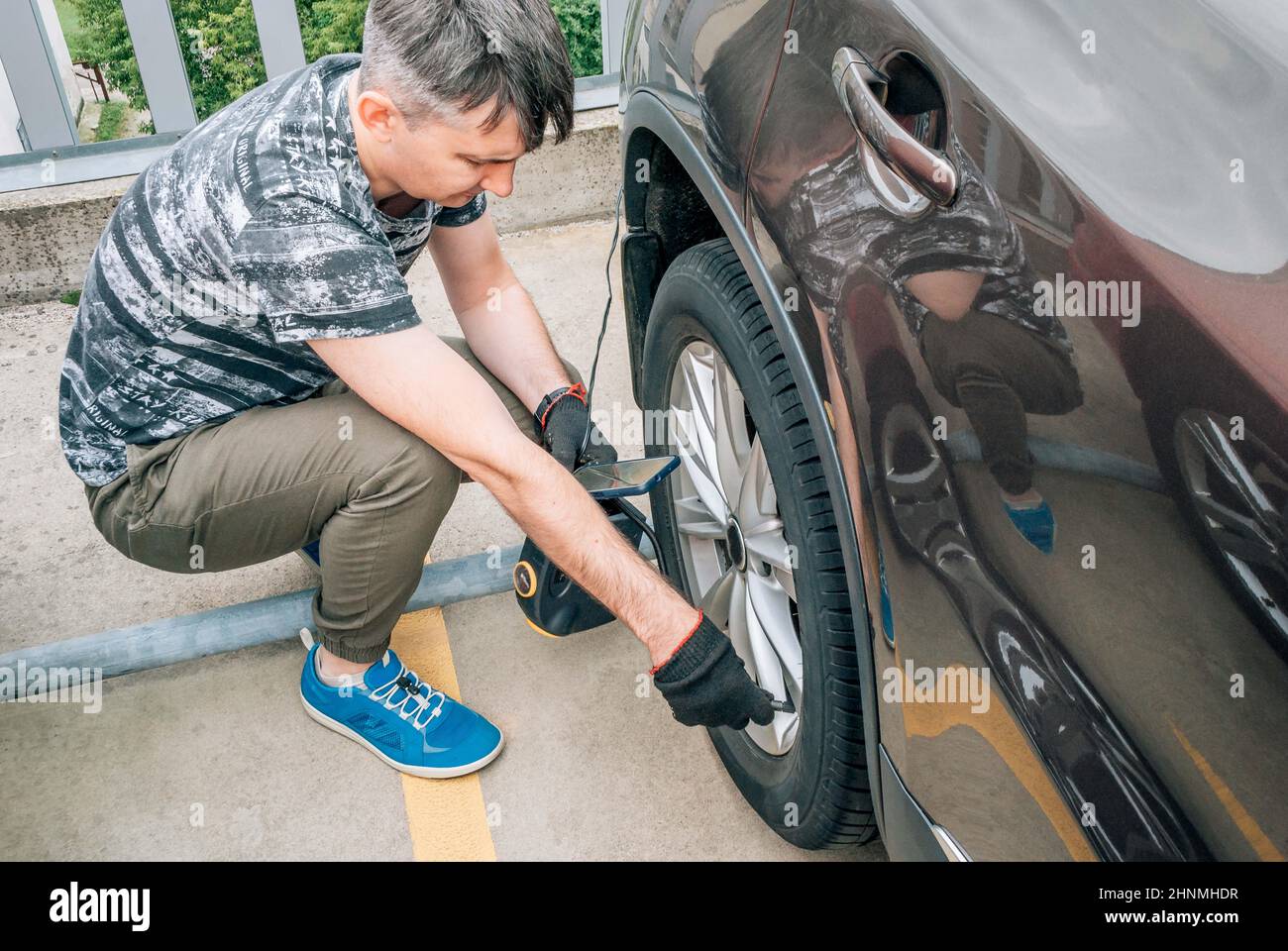 Ein Mann pumpt das Rad eines Autos mit einer Pumpe Stockfoto