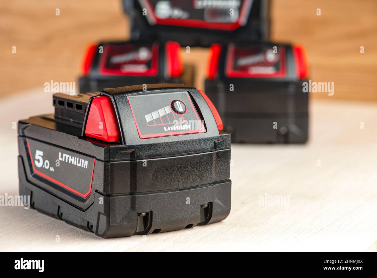 Akku für Akku-Bohrmaschine. Schrauberbatterie. Vier Batterien mit Ladeanzeige liegen auf einem Holzhintergrund Stockfoto