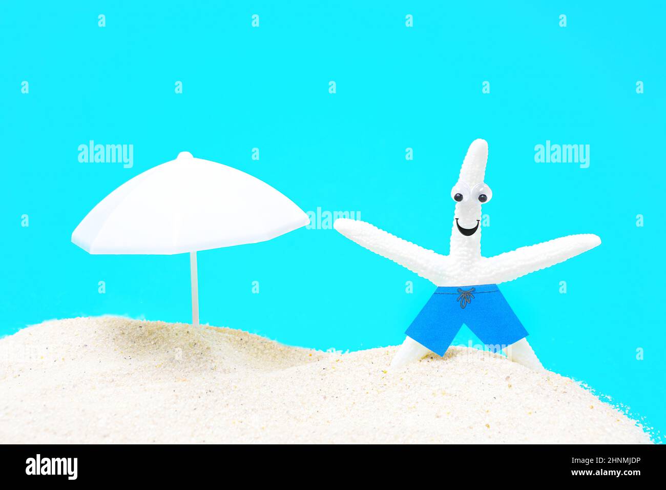 Lustige weiße Seesterne mit schönen Augen in blauen Badeshorts genießt die Sonne auf einem sandigen Strandurlaub. Stockfoto