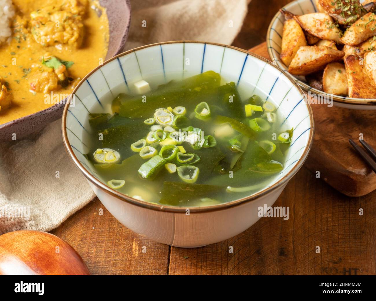 Traditionelle Algensuppe in einer weißen Schüssel mit etwas Essen auf einem Holztisch chinesische Suppe von oben Stockfoto