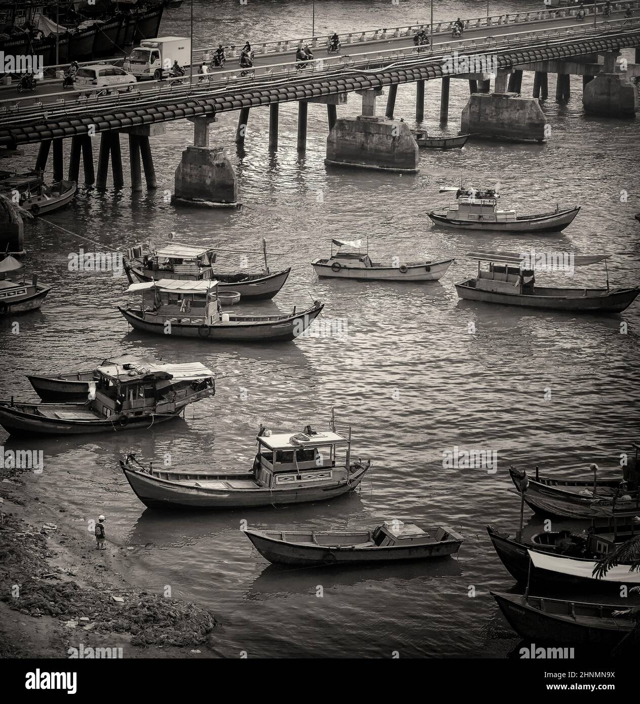 Ein Junge an der Küste schaut mit Booten auf den Fluss Stockfoto