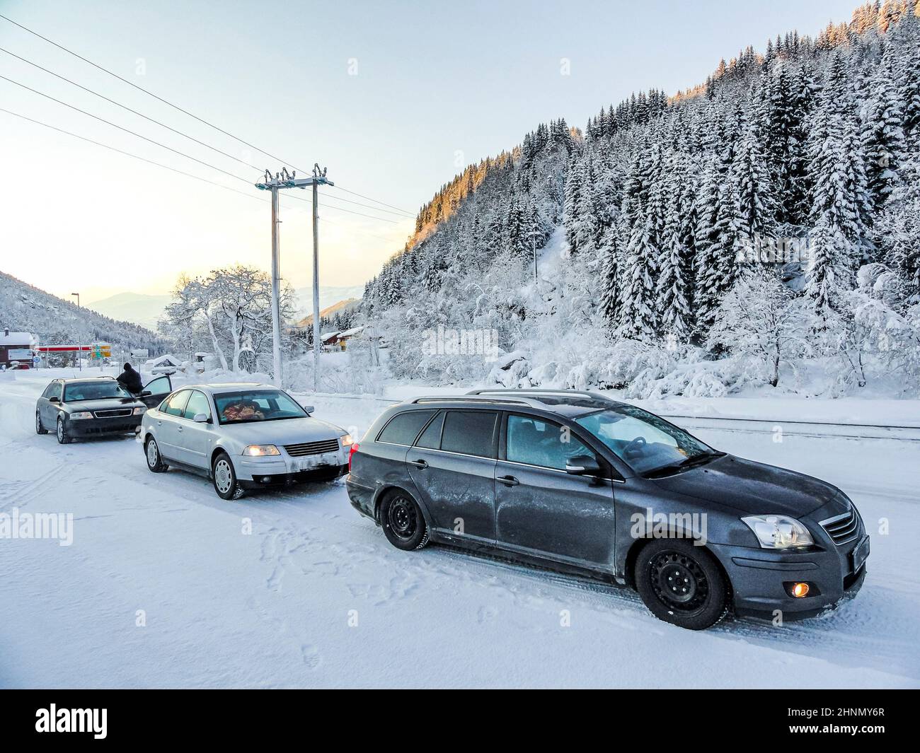 Autos halten in einer verschneiten Landschaft durch Berge Norwegen. Stockfoto
