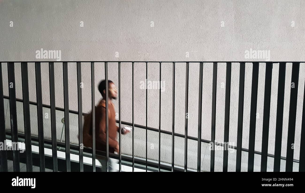 Eine Silhouette eines schwarzen Mannes, der hinter dem Metallgeländer die Treppe hinuntersteigt. Stockfoto