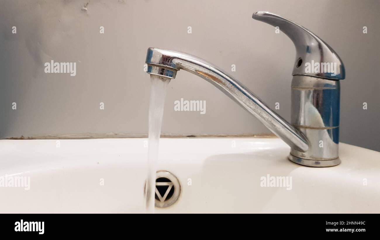 Alte und schmutzige Wasserhahn und weiße Keramik Waschbecken, Konzept der Reinigung, Reparatur oder Austausch eines Badezimmers, Toilette. Stockfoto