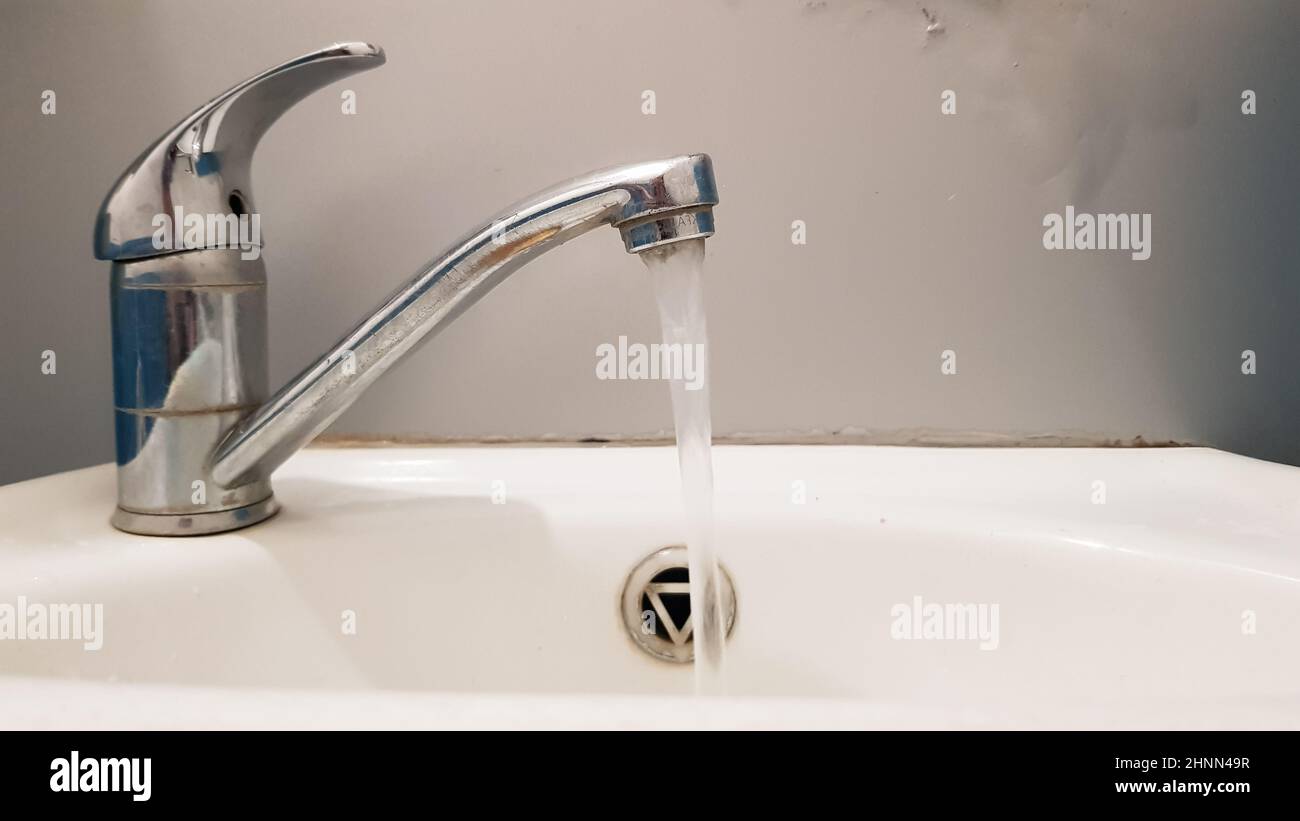 Alte und schmutzige Wasserhahn und weiße Keramik Waschbecken, Konzept der Reinigung, Reparatur oder Austausch eines Badezimmers, Toilette. Stockfoto