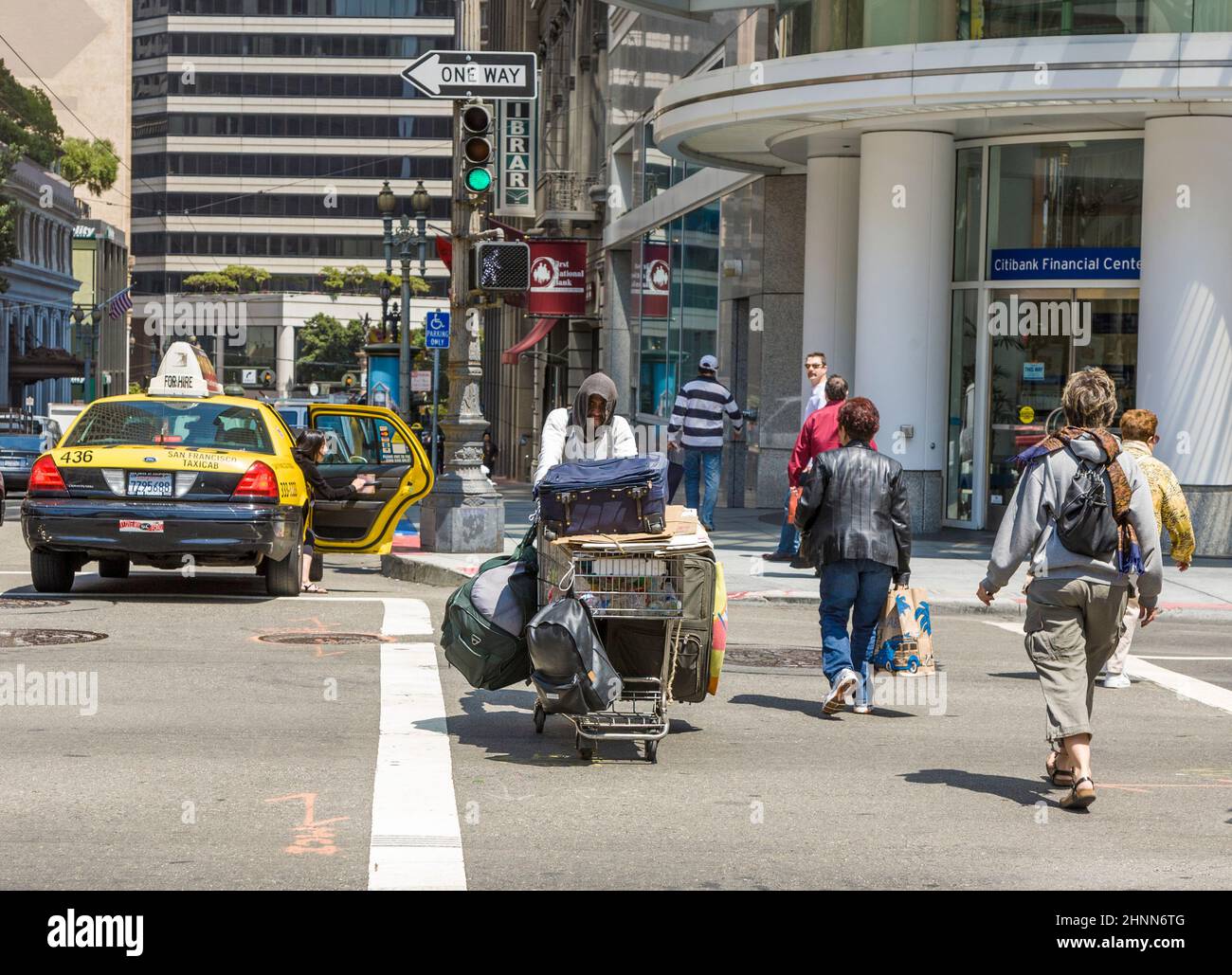 Obdachlose überqueren die Straße an einer Fußgängerüberführung mit grünem Licht in San Francisco. Stockfoto