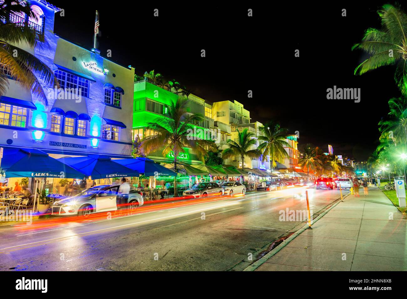 Bei Nacht laufen die Leute entlang des Ocean Drive mit berühmten Art-Deco-Hotels wie Colony und Pelican Stockfoto
