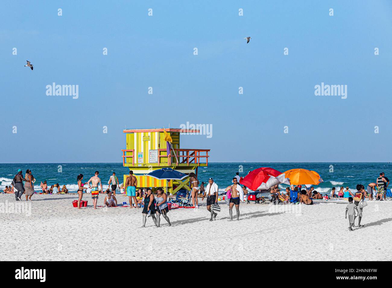 Die Menschen genießen South Beach in Miami Beach und sitzen vor dem farbenfrohen Rettungsschwimmerturm Stockfoto