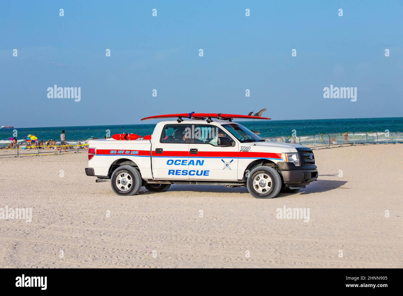 Die Menschen genießen South Beach in Miami Beach und die Ozeanrettungs-Autokontrollen für die Sicherheit mit einem Surfbrett oben Stockfoto