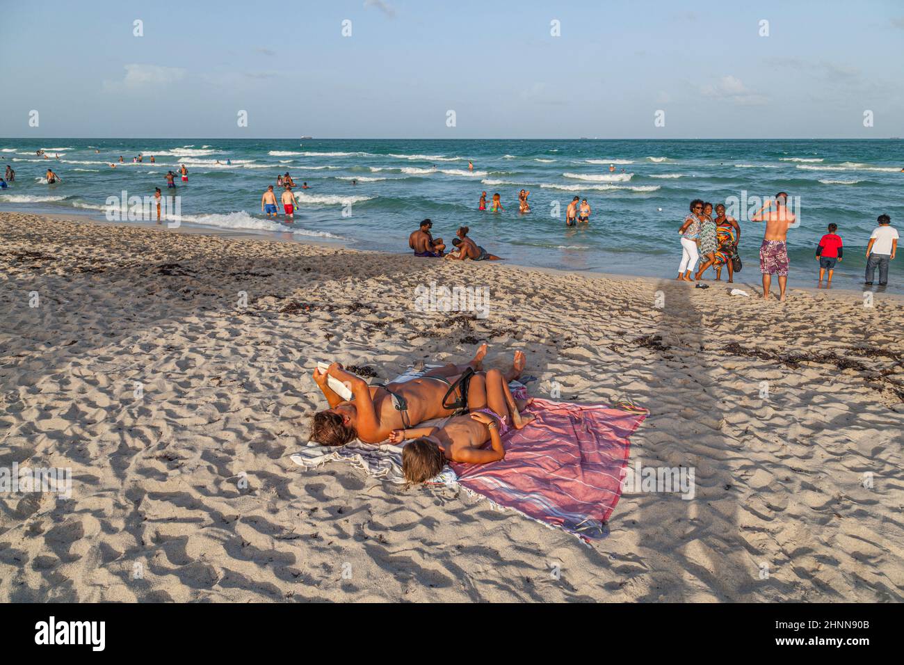 Die Menschen genießen den berühmten Sonnenuntergang am Südstrand in Miami Beach und entspannen sich in der Nachmittagssonne Stockfoto