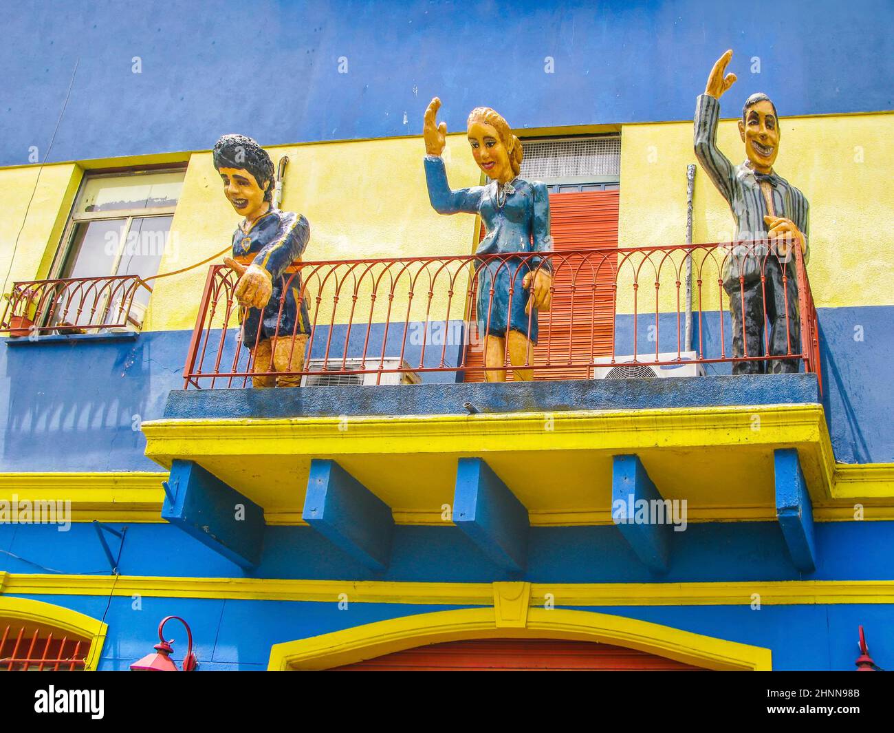Statuen grüßen von einem Balkon aus die Touristen besuchen die Caminito Straße, Buenos Aires, Argentinien. Caminito ist eine traditionelle Gasse, die sich in La Boca befindet Stockfoto