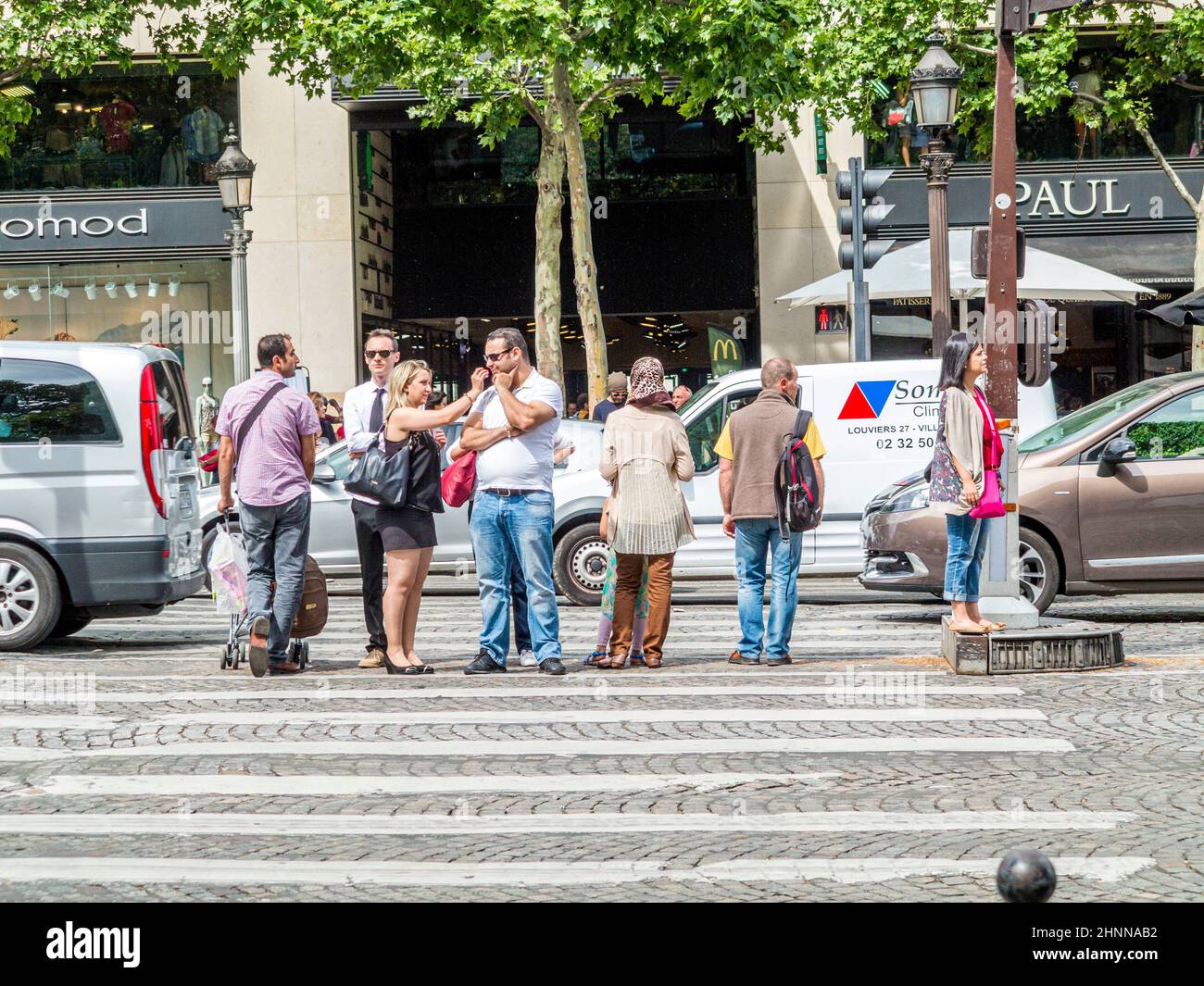 An einer Kreuzung im Herzen von Paris überqueren die Menschen die Straße an einer Straßenampel für Fußgänger.an der Champs d´ Elysees Stockfoto