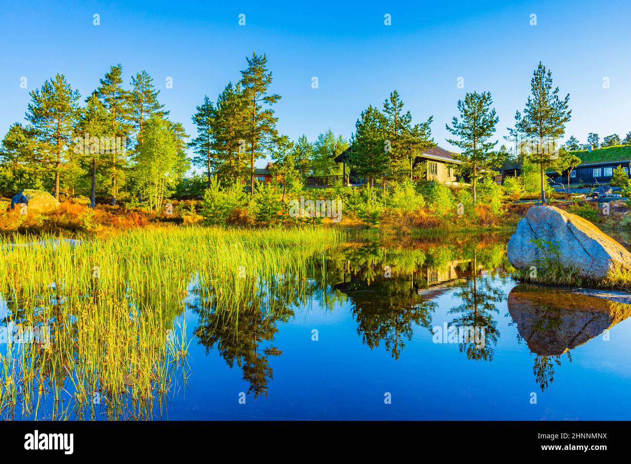 Morgenaufgang mit Spiegelung im Seenfluss in der Naturlandschaft Norwegens in Treungen Urlaubsresort in Nissedal Norwegen. Stockfoto