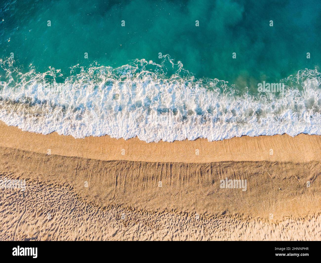 Top down Luftaufnahme eines sauberen Sandstrandes am Ufer eines wunderschönen türkisfarbenen Ligurischen Meeres, Italien Stockfoto
