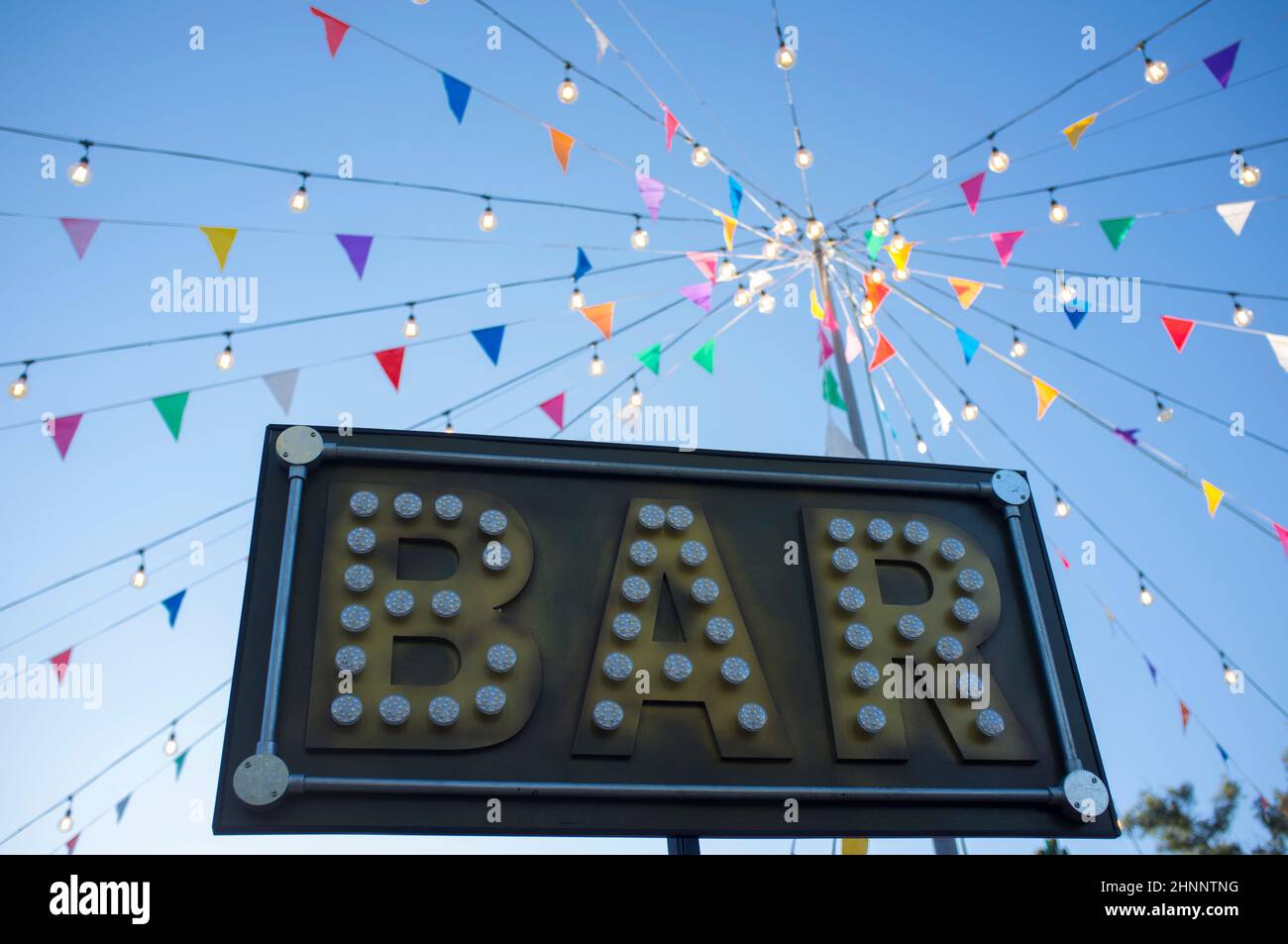 Bar-Banner mit bunten Wimpern und Glühbirnen auf Stange. Im Freien Party Hintergrund Stockfoto