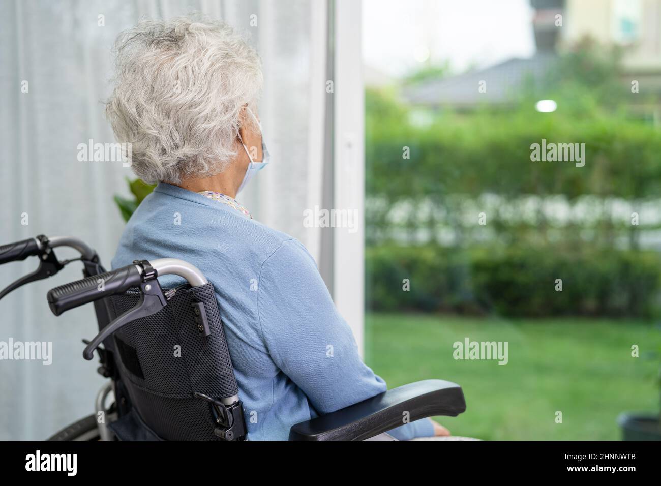 Eine ältere Frau, die auf einem Rollstuhl sitzt und aus dem Fenster