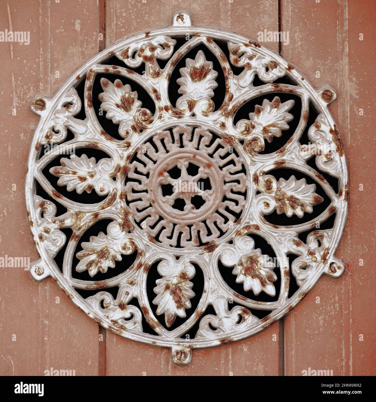 Altes rostiges Gußloch - großes rundes Blumendesign - Holzgaragentor. Tavira-Portugal-108 Stockfoto