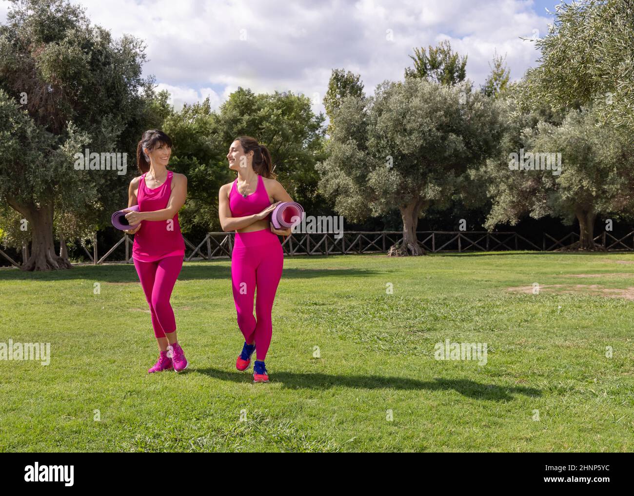 Zwei Frauen, die in einem Park mit gerollten Matten spazieren Stockfoto