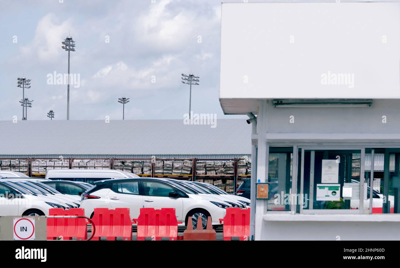 Neuwagen auf dem Parkplatz der Autofabrik. Automobilproduktion. Fahrzeugbestand wartet auf Verkauf. Parkplatz in der Autofabrik und Wachhaus für die Sicherheit. Automobilindustrie. Automobilgeschäft. Stockfoto