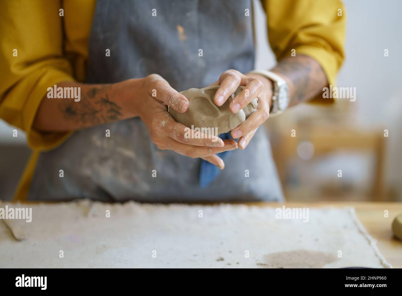 Weibliche Töpferkünstlerin Hände Formen rohen Ton. Keramikerin in Schürze bereitet sich auf die Gestaltung von Töpferwaren vor Stockfoto