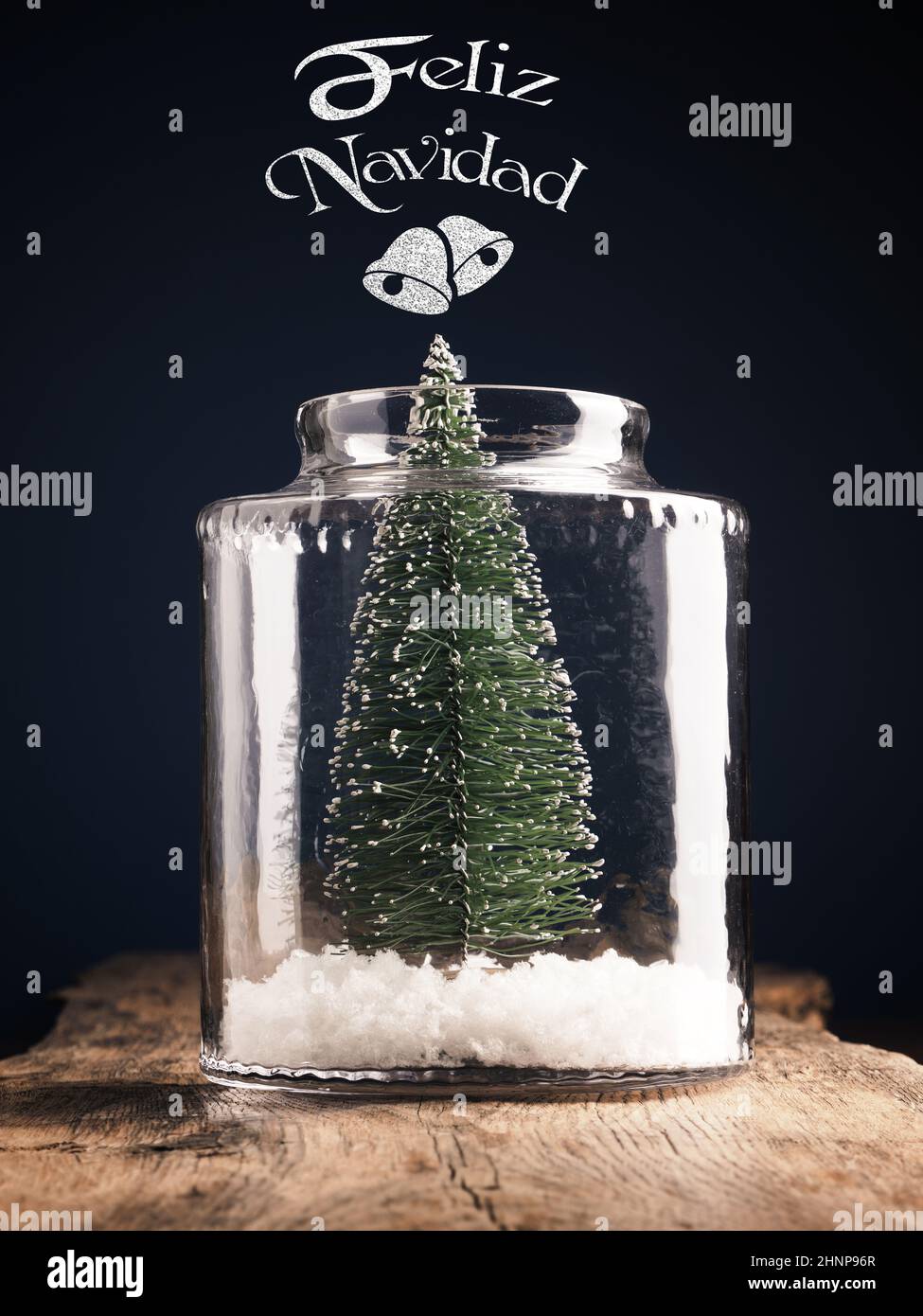 Ein Weihnachtsbaum im Glas mit Schnee, spanische Schriftzüge Frohe Weihnachten, Weihnachtskarte, Urlaubskonzept Stockfoto