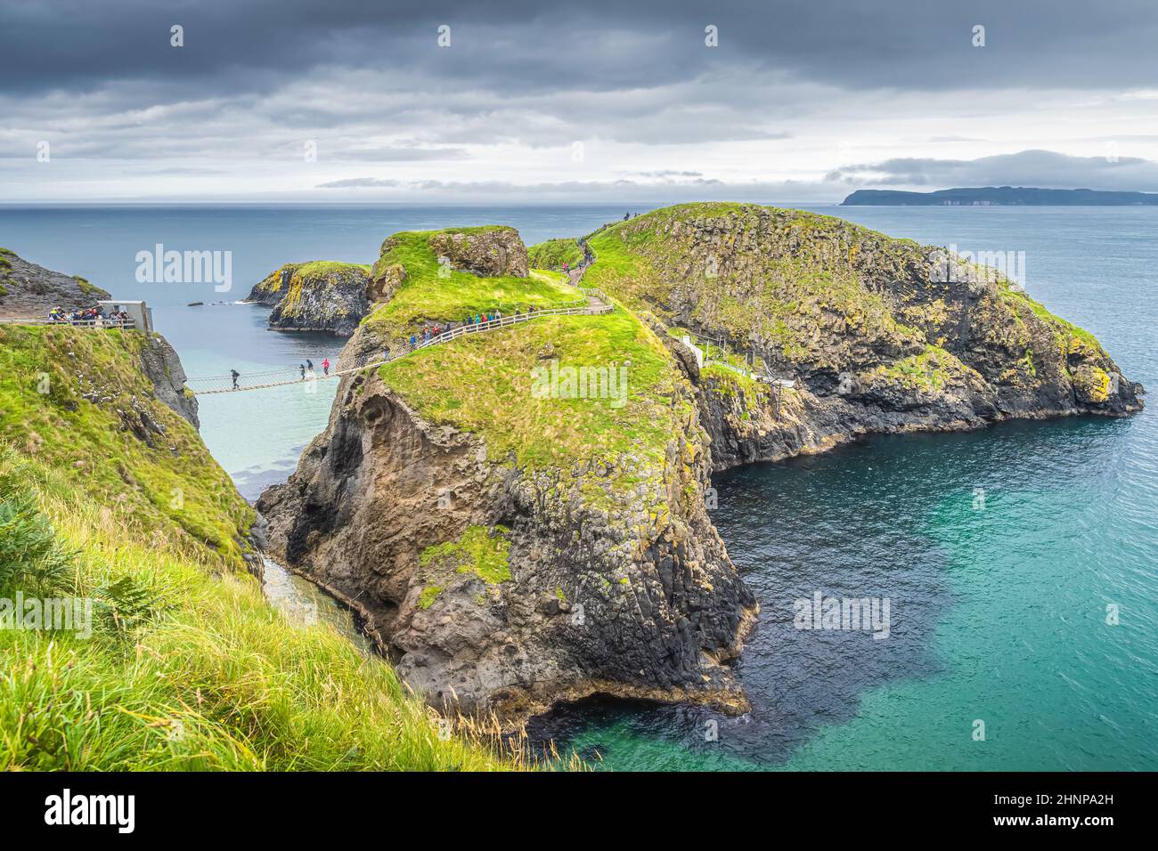 Menschen auf der Carrick a Rede Seilbrücke und landschaftlich reizvolle Insel, umgeben vom türkisfarbenen Atlantischen Ozean Stockfoto