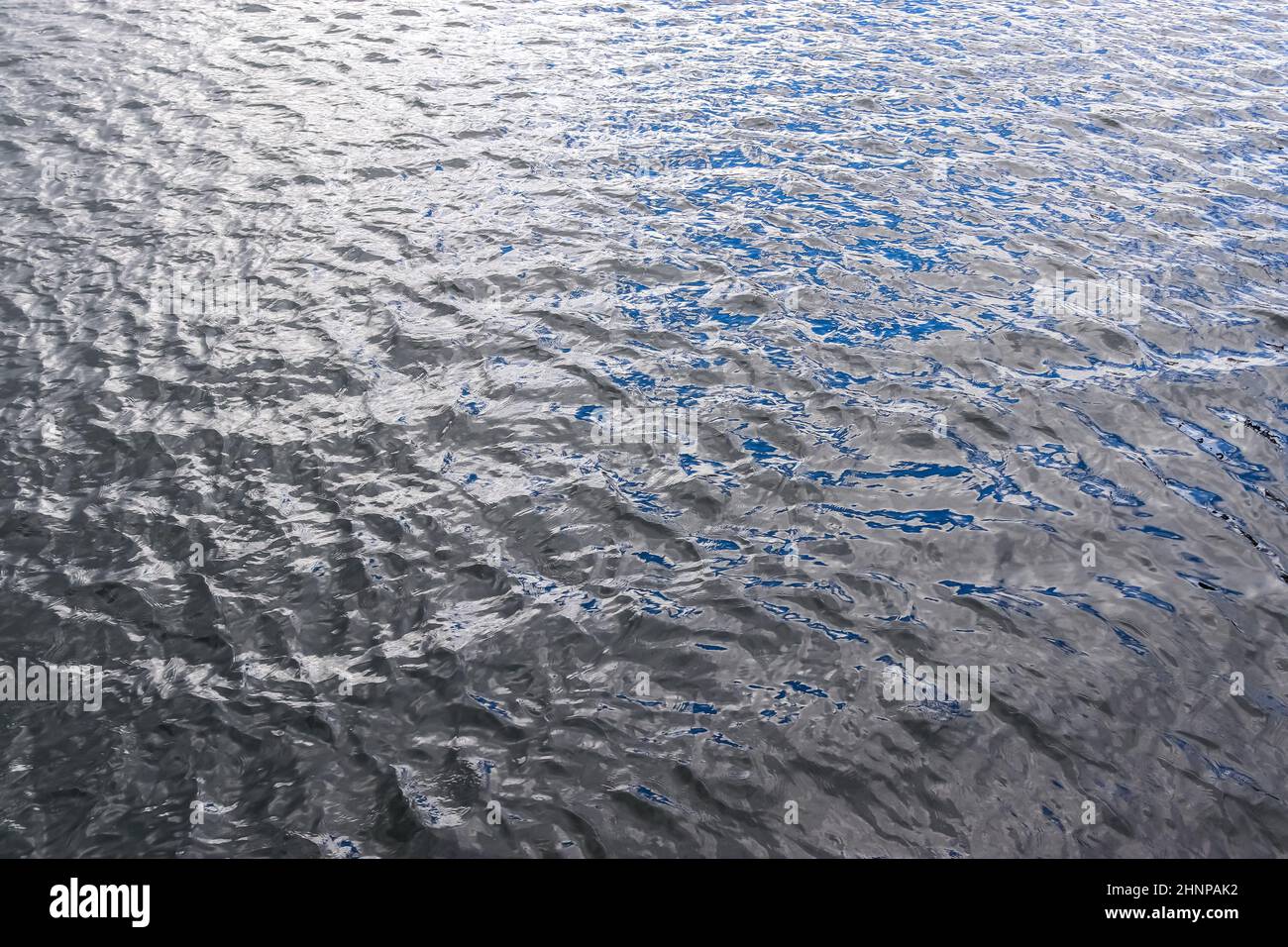 Detaillierte Nahaufnahme auf Wasseroberflächen mit Wellen und Wellen und das Sonnenlicht, das an der Oberfläche reflektiert wird Stockfoto