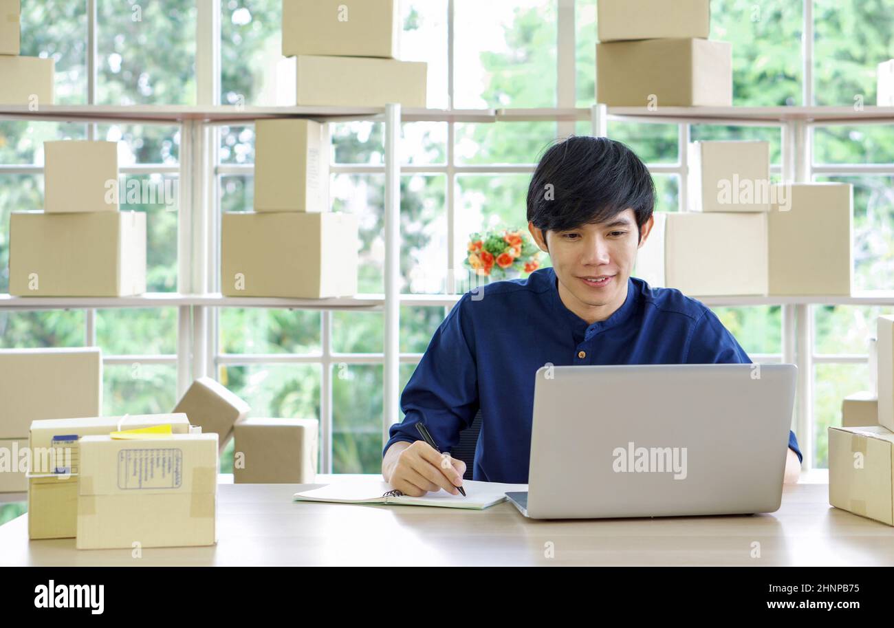 Junger asiatischer Unternehmer, der Produkte im Home Office kontrolliert. „Work from Home“-Konzept. Stockfoto