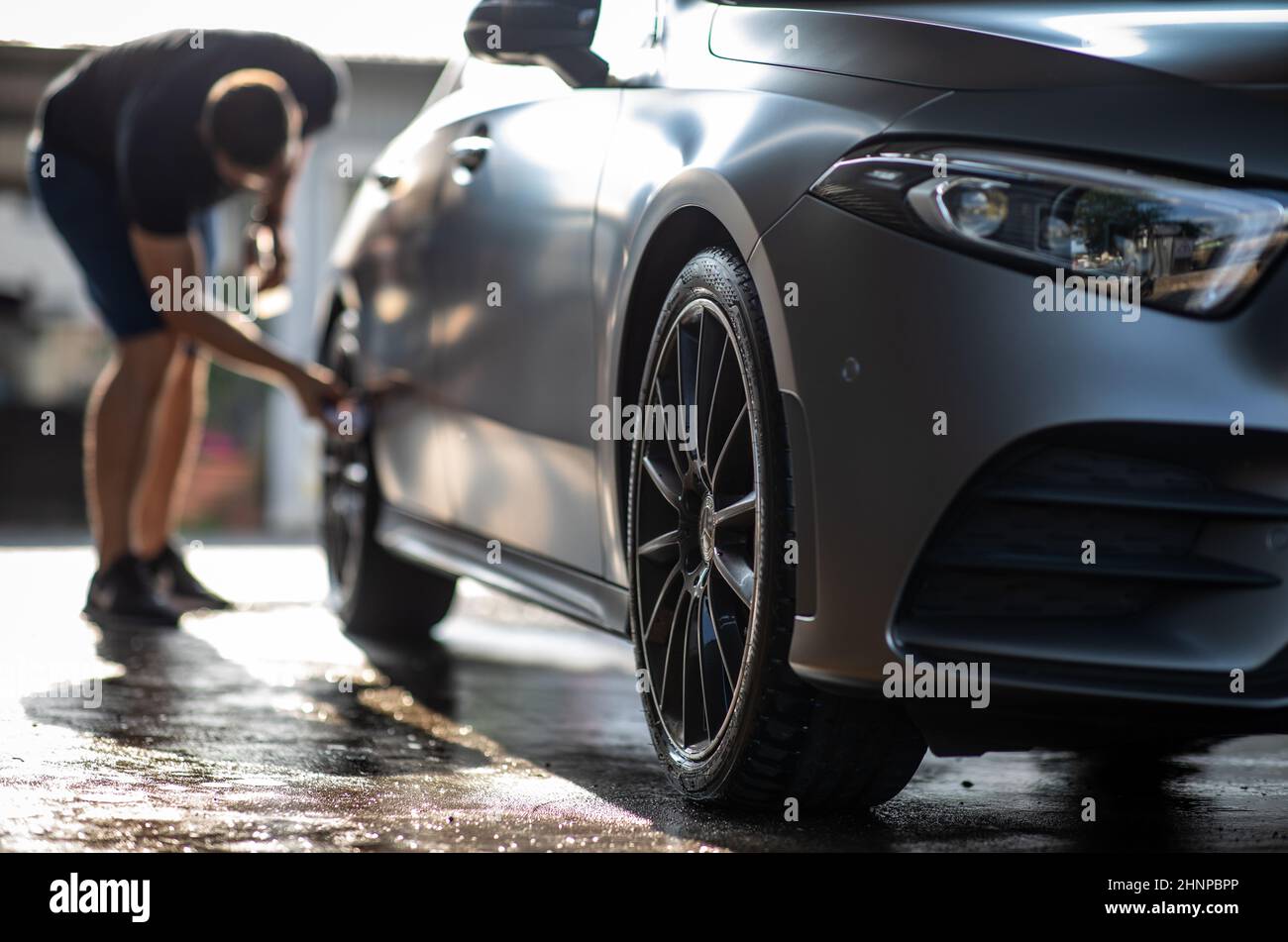 Auto in einer Waschanlage - Nagelneues Auto Besitzer über seine Schöne Räder Stockfoto