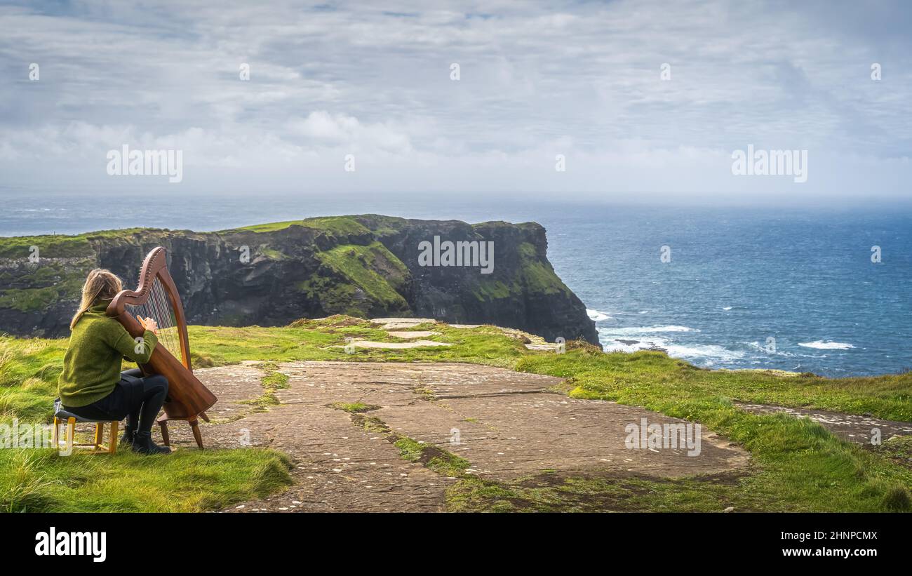 Frau spielt Harfe auf den legendären Cliffs of Moher, Irland Stockfoto