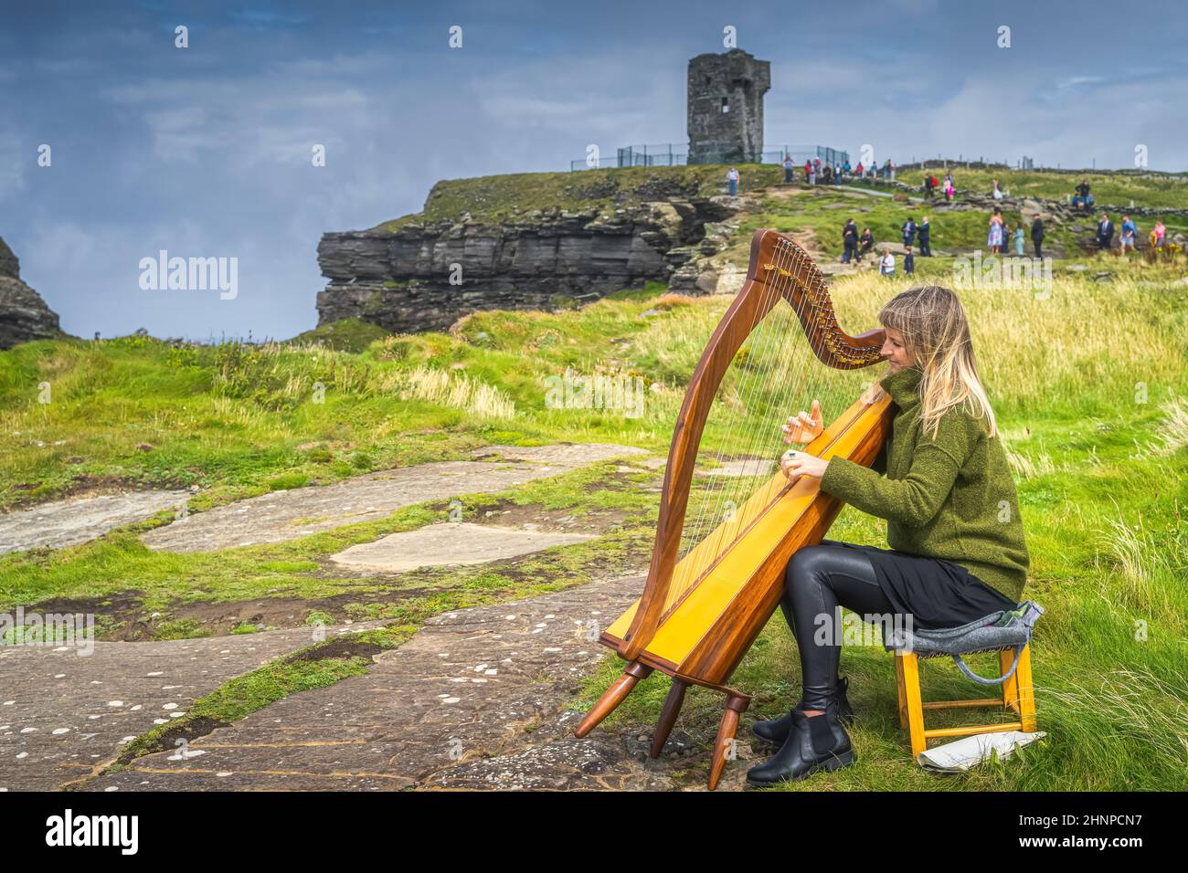 Frau spielt Harfe auf den legendären Cliffs of Moher, Wild Atlantic Way, Irland Stockfoto