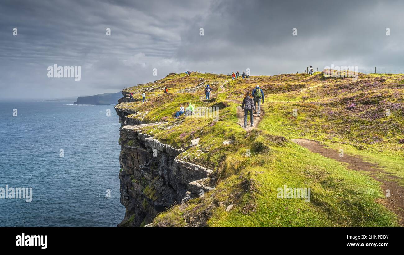 Eine Gruppe von Touristen, die wandern und die berühmten Cliffs of Moher, Irland, besichtigen Stockfoto