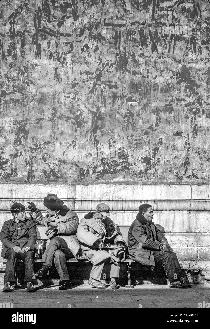 Chinesen in grün-blauem Parka sitzen auf einer Bank vor der verbotenen Stadt in Peking, China Stockfoto