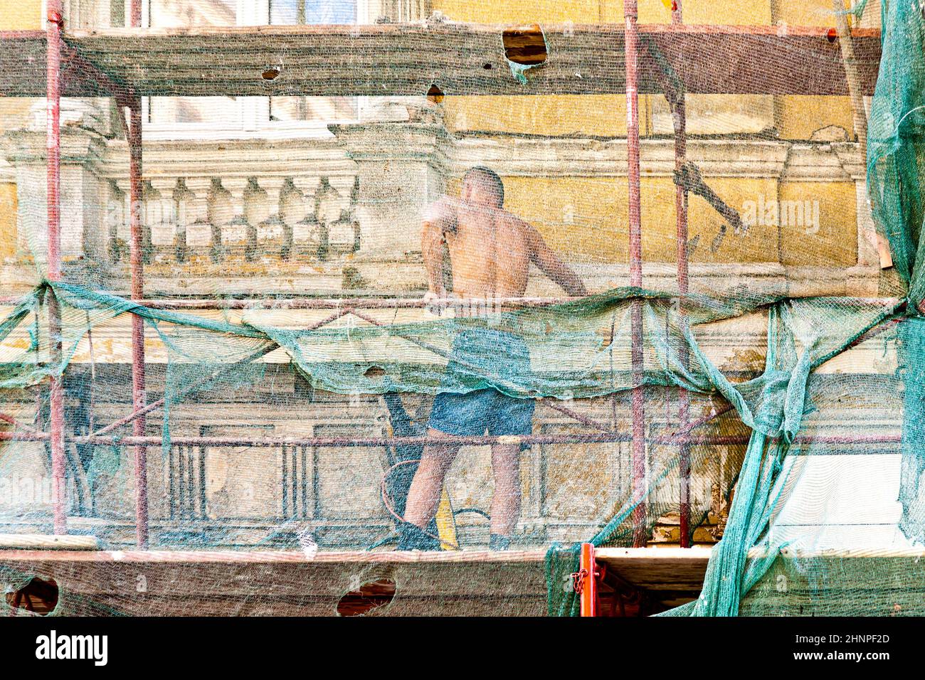 Der Mensch restauriert die Fassade von Gebäuden des 19th. Jahrhunderts in Wien, Österreich. Er ist durch ein Netz geschützt. Stockfoto