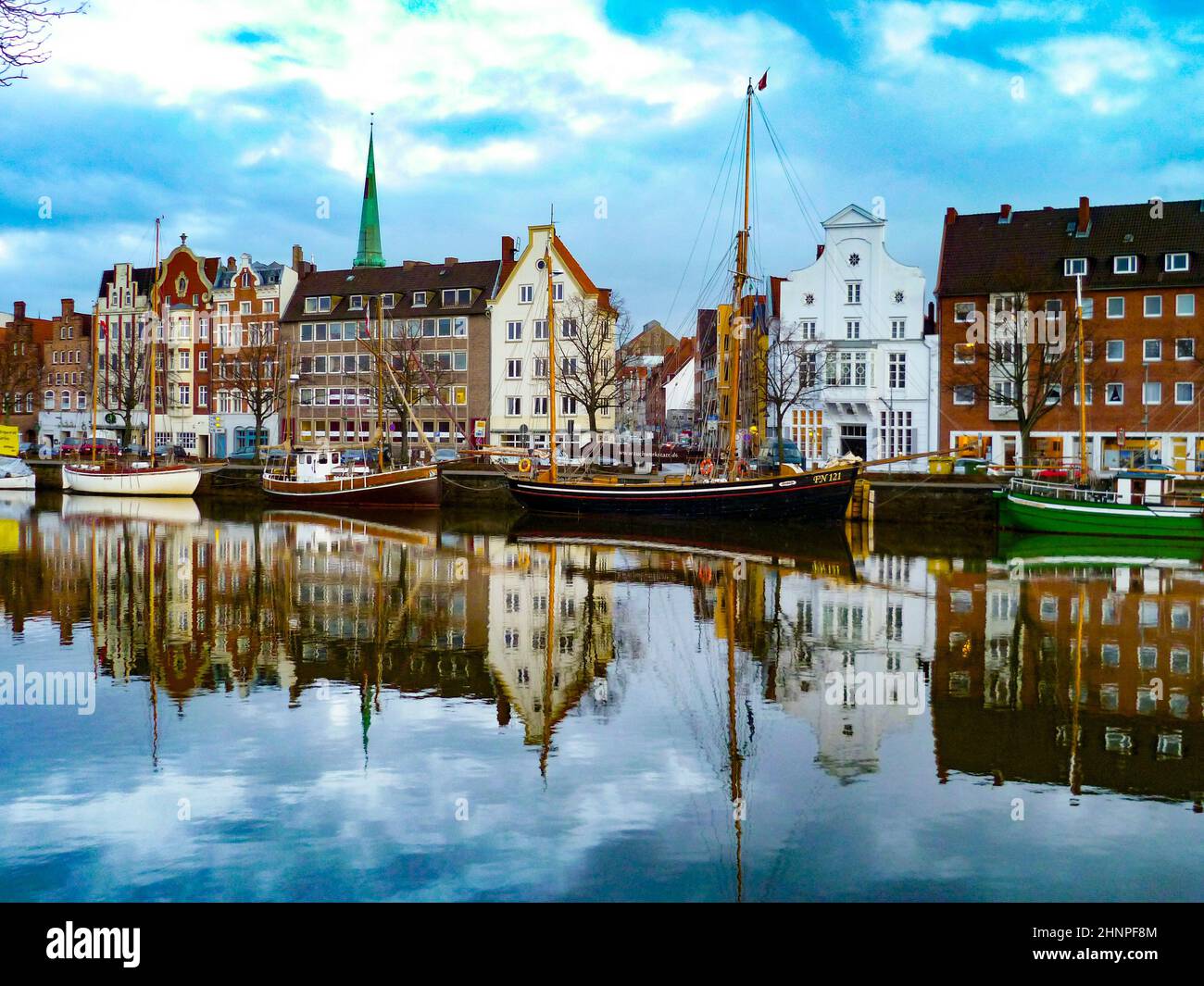 Schöner Blick auf die TRAVE und den Pier in Lübeck mit Spiegelungen im Hafen. Stockfoto