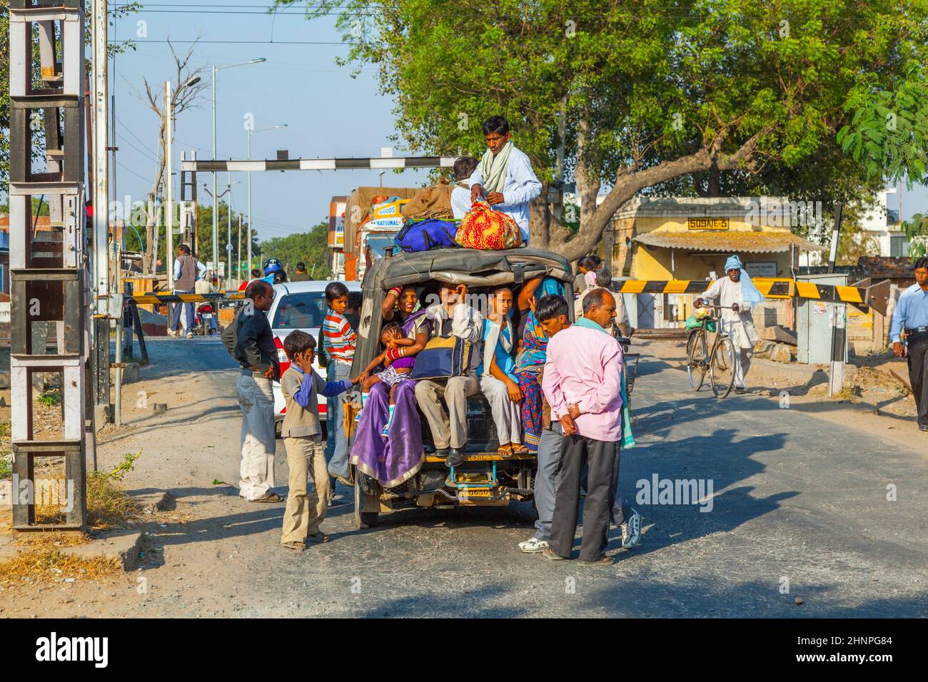Die Menschen warten am Bahnübergang in der Nähe von Fatehpur Sikri, Indien. Autos sind mit Menschen und Gütern überladen Stockfoto