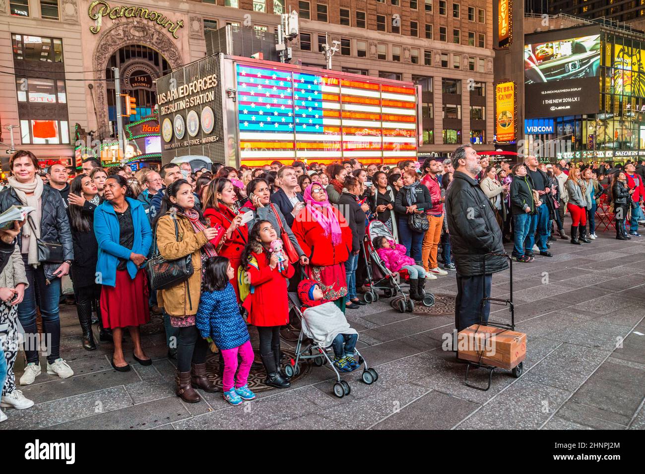 Die Leute sehen die öffentliche Fernsehsendung auf einem Bildschirm am Times Square bei Nacht Stockfoto