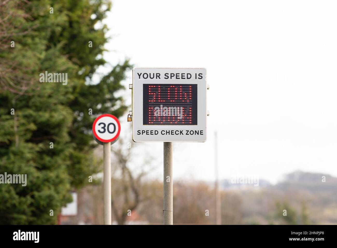 Slow Down-Zeichen auf Geschwindigkeitsanzeige Gerät als Fahrzeuggeschwindigkeiten in ländlichen 30mph Zone - England, Großbritannien Stockfoto